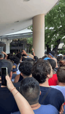 a crowd of people are gathered outside of a building with one man wearing a hat that says ' miami '