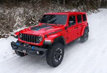 a red jeep is driving on a snowy road .