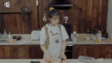 a woman in an apron is preparing food in a kitchen with a question mark on the wall behind her