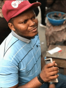 a man wearing a red hat that says oreo is holding a cell phone