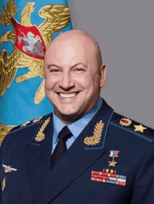 a man in a military uniform is smiling in front of a blue flag with an eagle on it