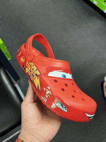 a person is holding a red shoe with lightning mcqueen and the number 95 on it