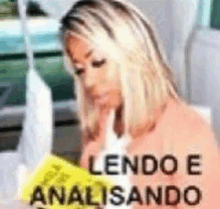 a woman is sitting at a table reading a book with the words lendo e analisando written on it .