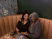 two women sit at a table in front of a sign that says ' ups '