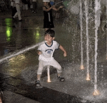 a young boy is playing in a water fountain .