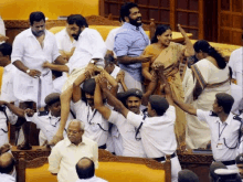 a man in a white shirt is being lifted up by a group of people