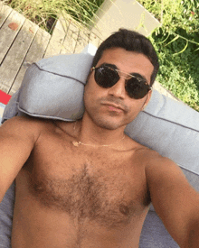 a shirtless man is laying on a couch wearing sunglasses