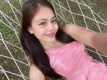 a woman in a pink dress laying on a hammock