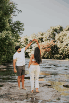 a man and a woman are dancing in front of a body of water