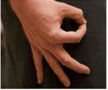 a close up of a person 's hand making a circle with their fingers on a black surface .