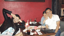 a group of people sitting at a table with plates of food and drinks