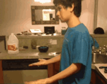 a man in a blue shirt is standing in front of a kitchen counter with a gallon of apple cider vinegar on it