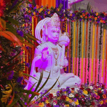 a statue of a deity is surrounded by flowers and plants