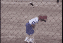 a baseball player with the number 28 on his jersey is swinging a bat at a ball behind a chain link fence .