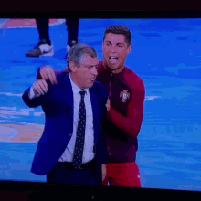 a man in a suit and tie stands next to a man in a soccer uniform with the word portugal on the front