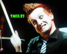 a man with red hair is holding a drum stick and smiling with the words smile behind him