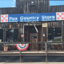 the front of a fox country store with a blue sign above the door