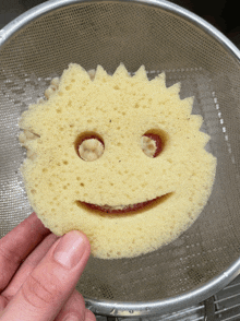 a person is holding a sponge with a smiley face cut into it