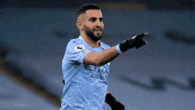 a soccer player wearing a blue etihad airways jersey points at something