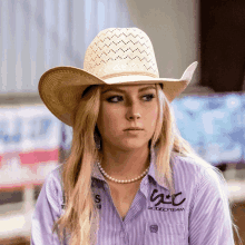 a woman wearing a cowboy hat and a shirt that says ac rodeo team on it