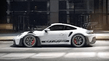 a white porsche 911 gt3 rs is parked on the side of a city street .