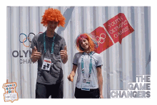 a man and a woman are posing for a photo in front of a sign for the youth olympic games