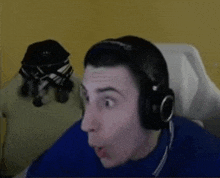 a man wearing headphones and a blue sweater is making a surprised face