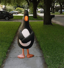 a statue of a penguin standing on the sidewalk