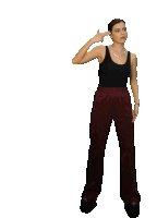 a woman in a black tank top and maroon pants is pointing her finger at her head