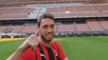 a man wearing a red and black puma shirt is giving a thumbs up