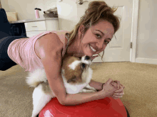 a woman is laying on a red ball with her dog