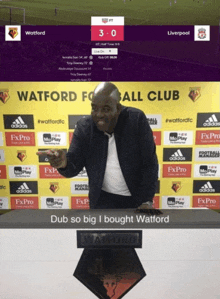 a man standing in front of a wall that says watford