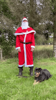 a man dressed as santa claus is standing next to a dog