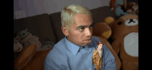 a man with blonde hair is holding a doll in his hand