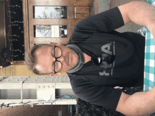 a man wearing glasses and a black under armour shirt sits at a table outside