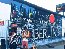 a man standing in front of a wall that says berlin on it