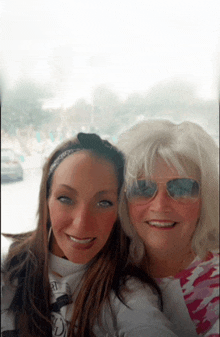 two women posing for a picture with one wearing sunglasses and the other wearing a bandana