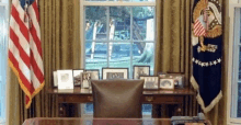 a desk with a chair in front of a window with american flags on it