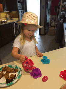 a little girl in a straw hat is pouring tea into a teapot