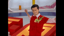 a man wearing a red sweater with a dragon on it is standing in front of a large number 7 .