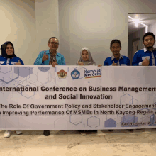 a group of people holding up a banner that says international conference on business management and social innovation