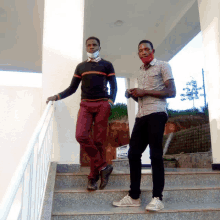 a man wearing a mask stands next to another man on the stairs