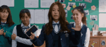 a girl in a school uniform is holding a cell phone in her hand