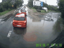 a red car is driving down a flooded road with a billboard in the background that says ' skoda '