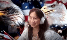 a woman wearing headphones is giving a thumbs up in front of an american flag and eagle .