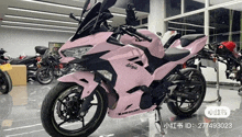 a pink and black kawasaki ninja motorcycle is parked in a garage .