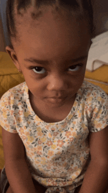 a little girl wearing a yellow and white floral shirt