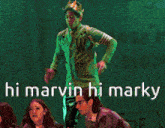 a man in a green jacket and a crown stands on a stage with the words hi marvin hi marky