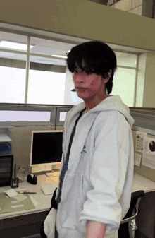 a man standing in front of a desk with a computer and a sign that says ' e ' on it