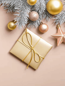 a gift wrapped in gold paper is surrounded by gold christmas decorations